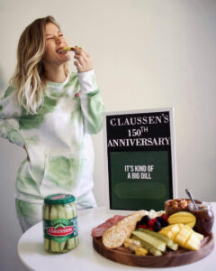 Girl eating Claussen Pickle with Sweatsuit on